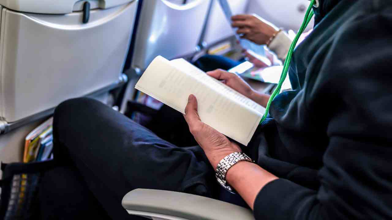 a person sitting on an airplane reading a book