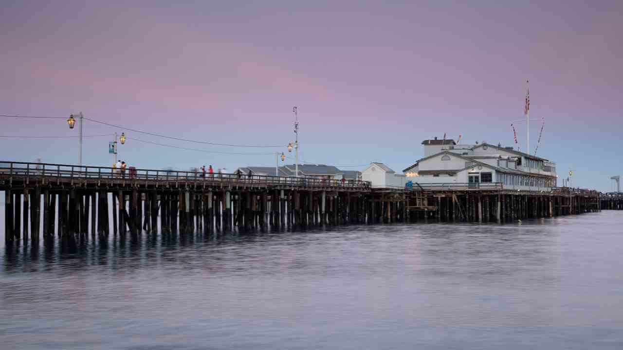 a pier with a house on it in the middle of the ocean