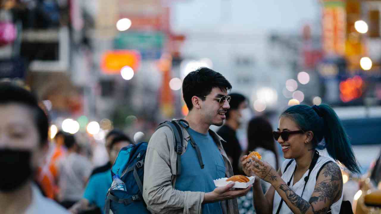 Two people eating food on a busy street