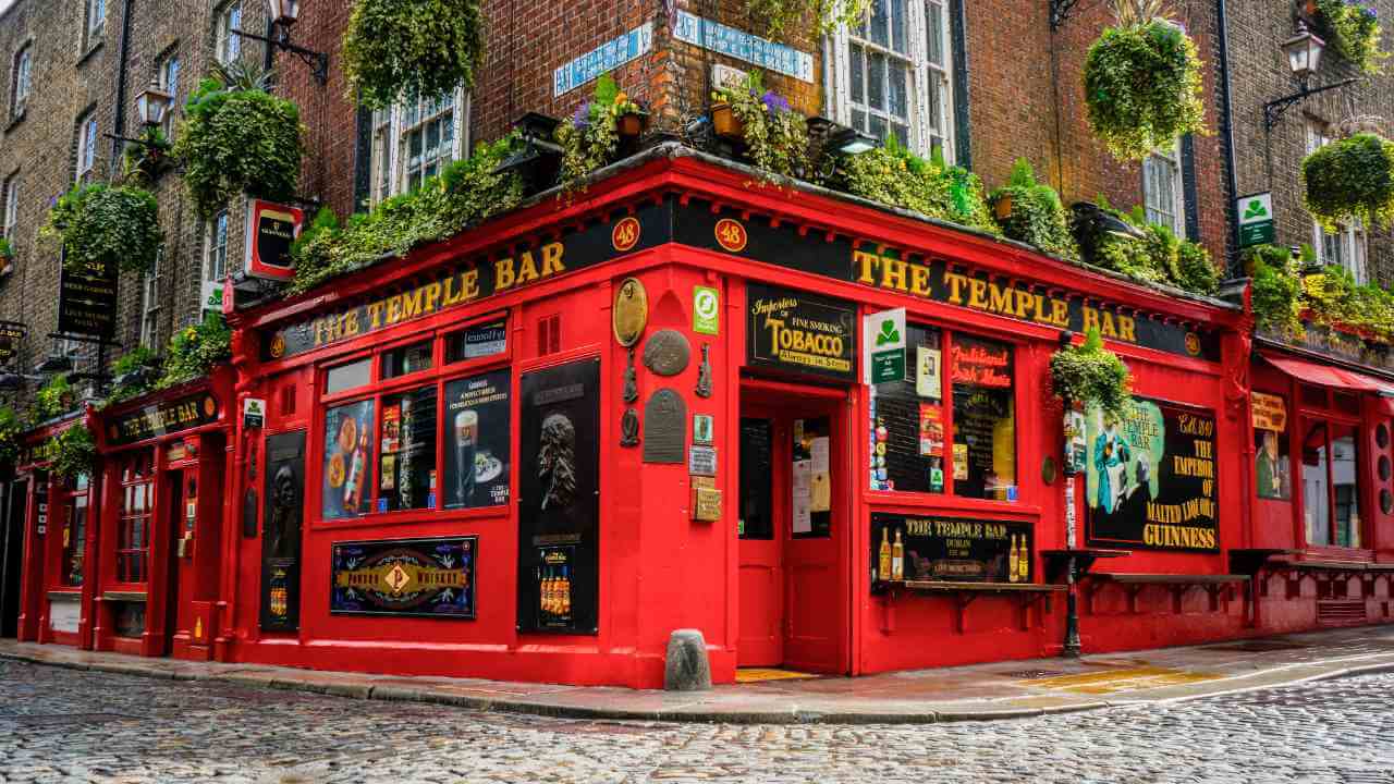 a red pub on a cobblestone street in dublin, ireland