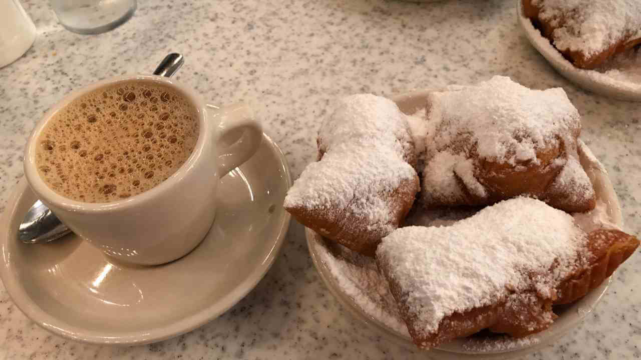 a white plate topped with powdered sugar and a cup of coffee