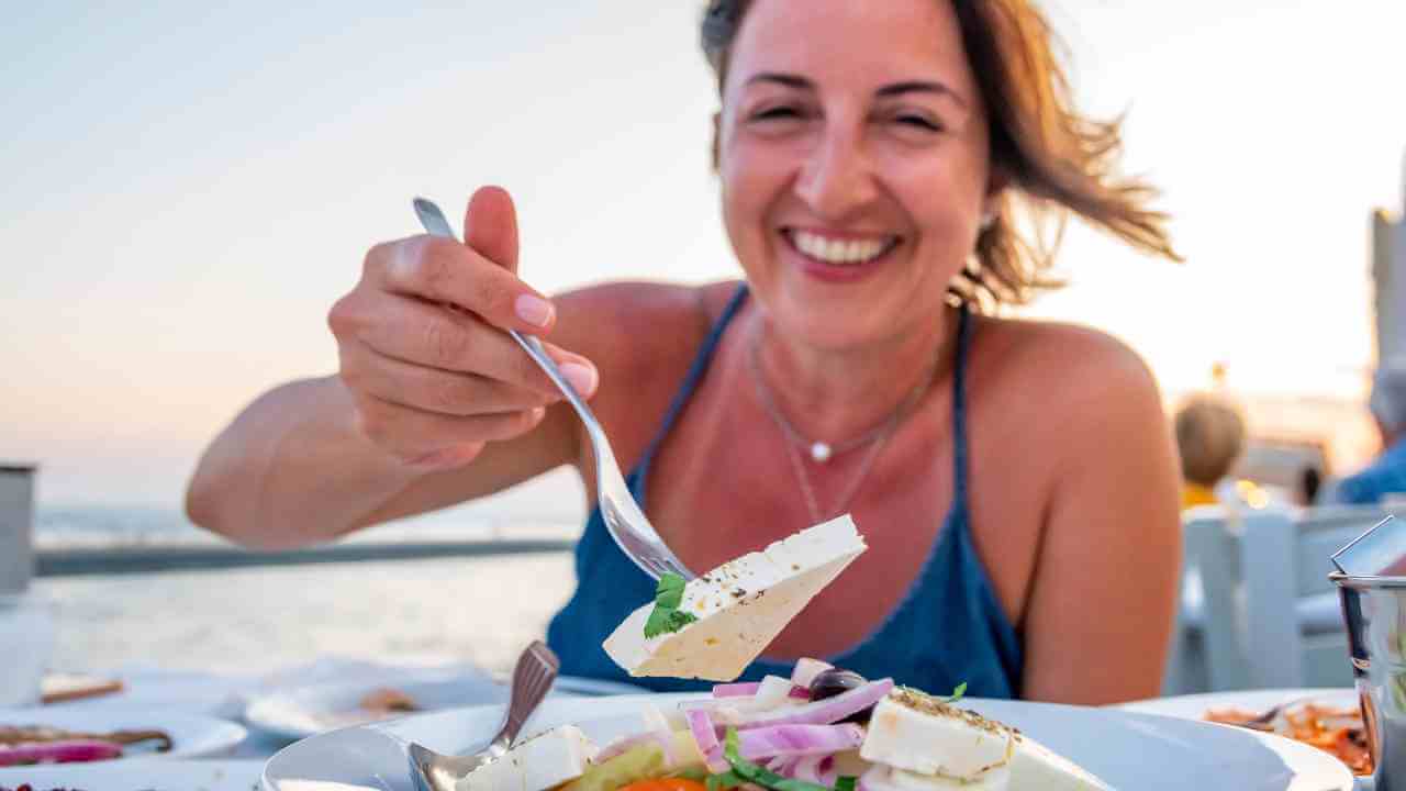 a person is eating a plate of food in front of the ocean