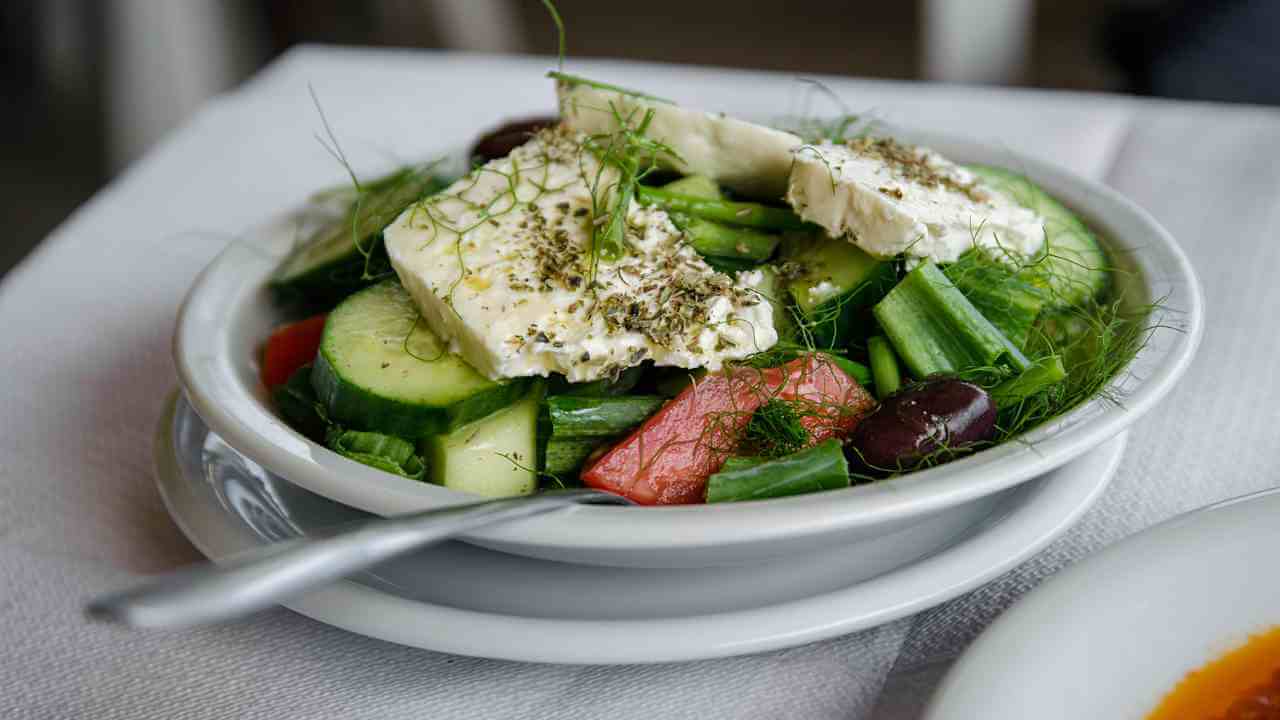 a bowl of greek salad with cucumbers, tomatoes and feta cheese