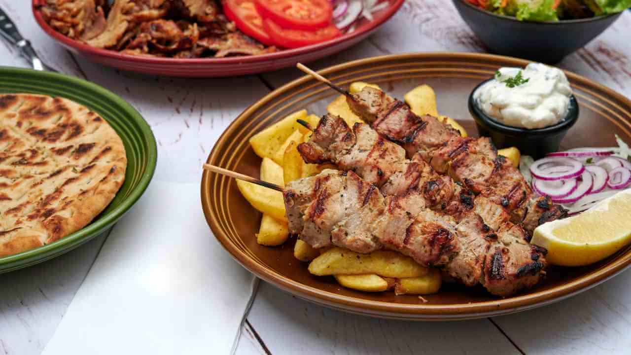 grilled chicken kebabs and french fries on a wooden table