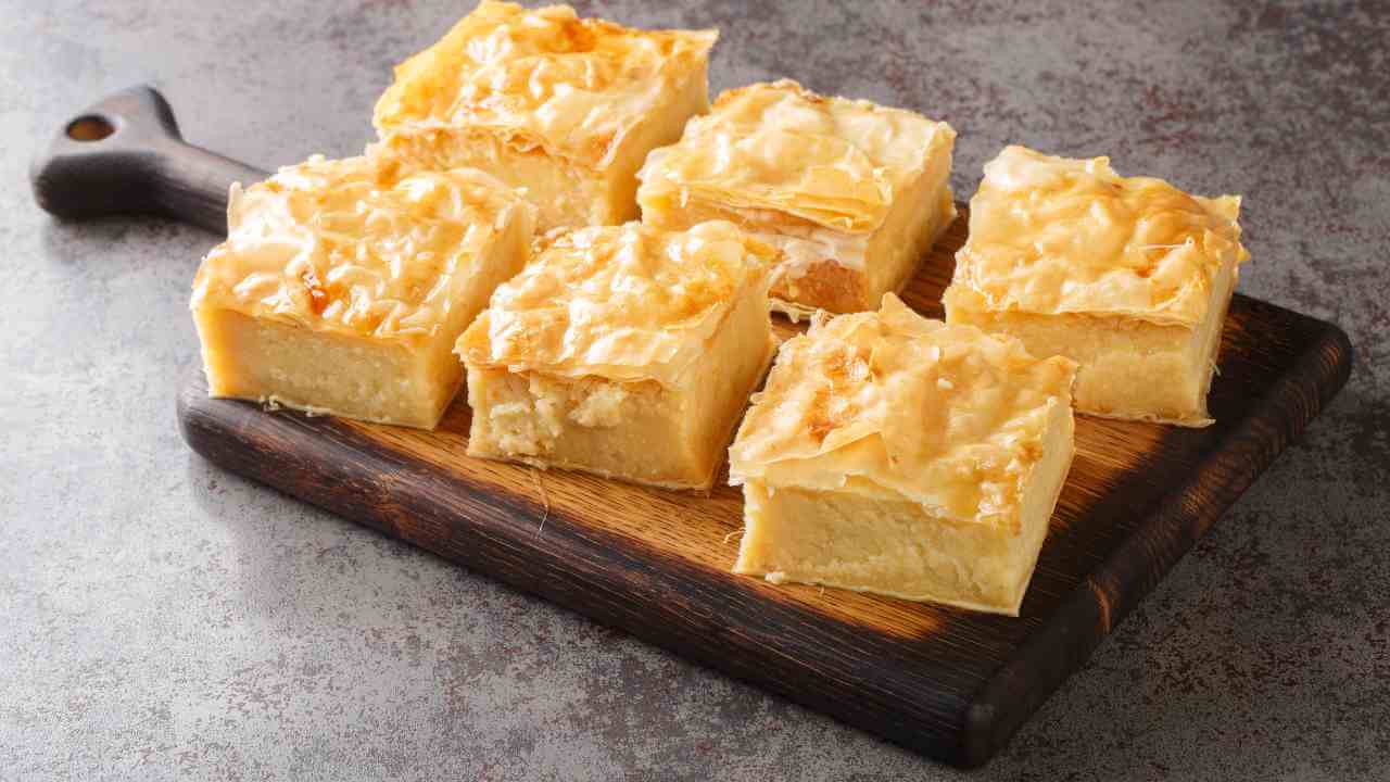 greek custard pie on a wooden cutting board