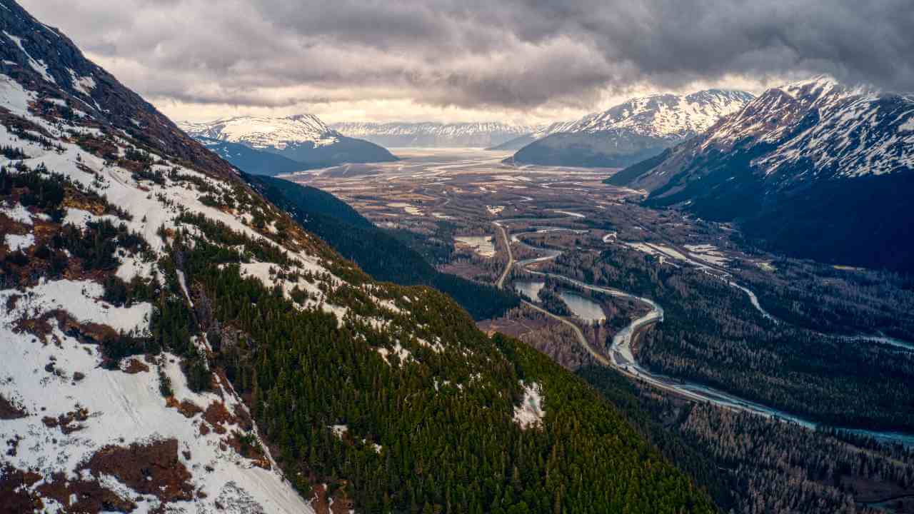 an aerial view of a snowy mountain range with a river running through it