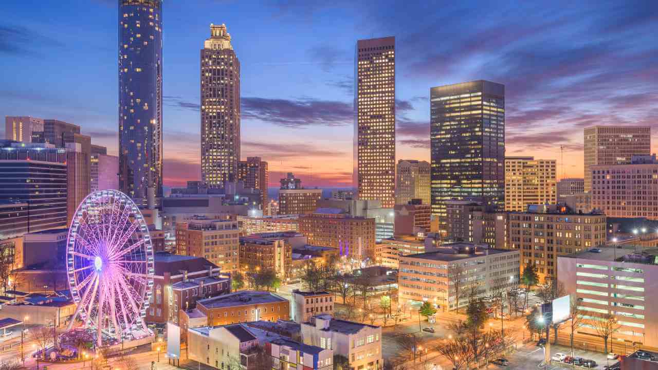 the skyline of atlanta at dusk with a ferris wheel in the foreground