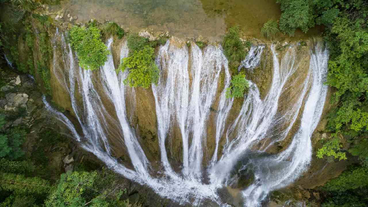 an aerial view of a waterfall in the middle of a forest