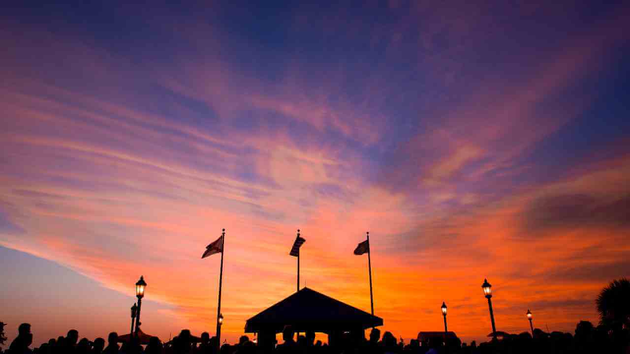 silhouettes of people standing in front of a building at sunset