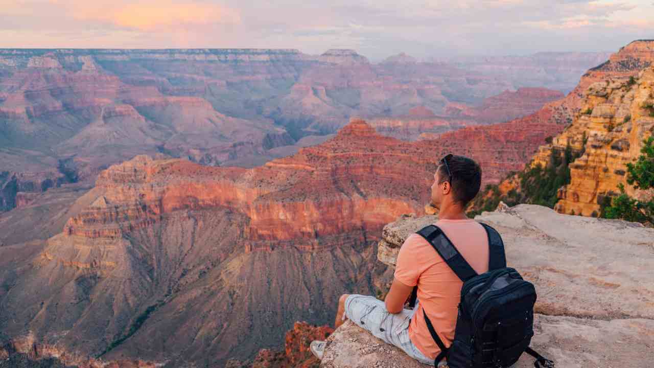 A person sitting at the edge of the Grand Canyon in Arizona.