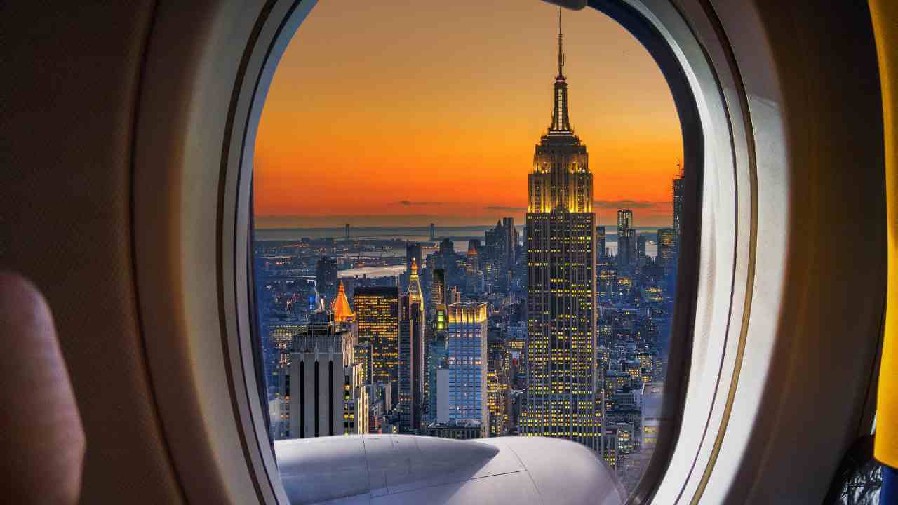 the empire state building seen through the window of an airplane at sunset