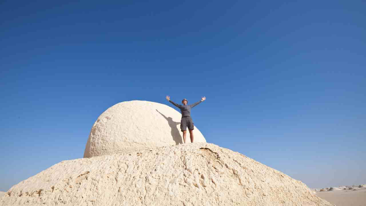 a person standing on top of a sand dune in the desert