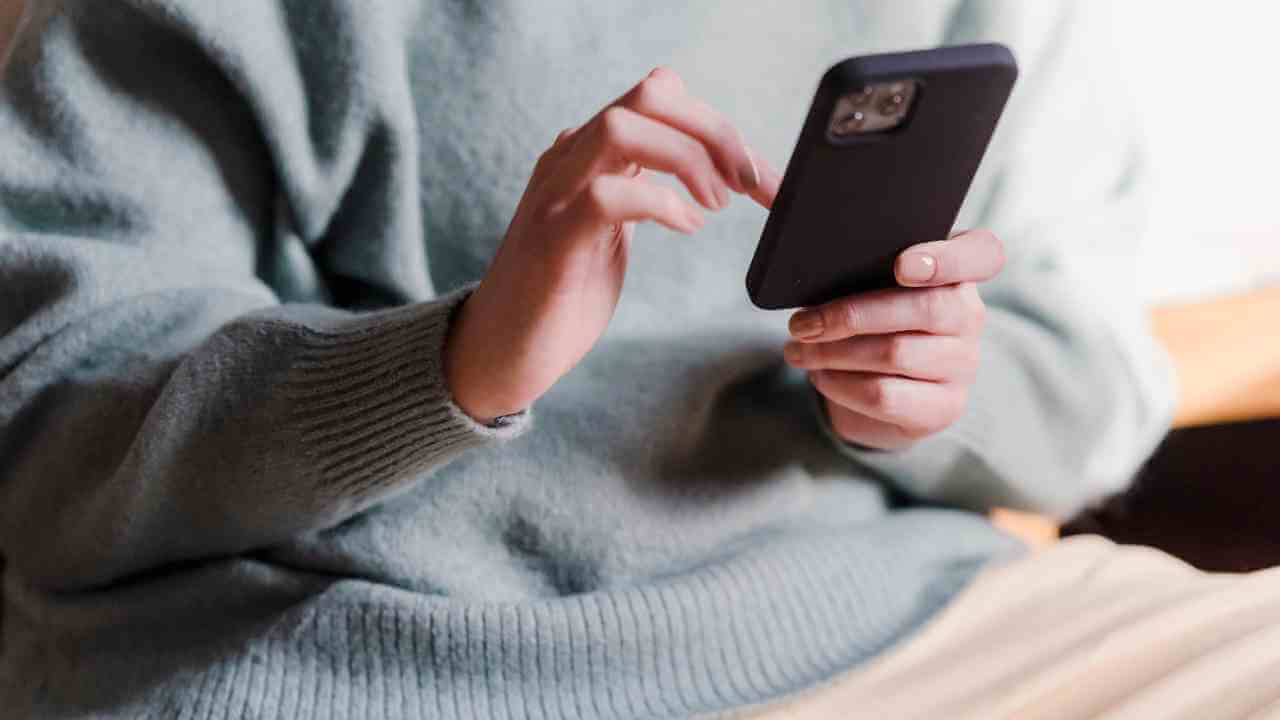 a person sitting on a couch holding a cell phone