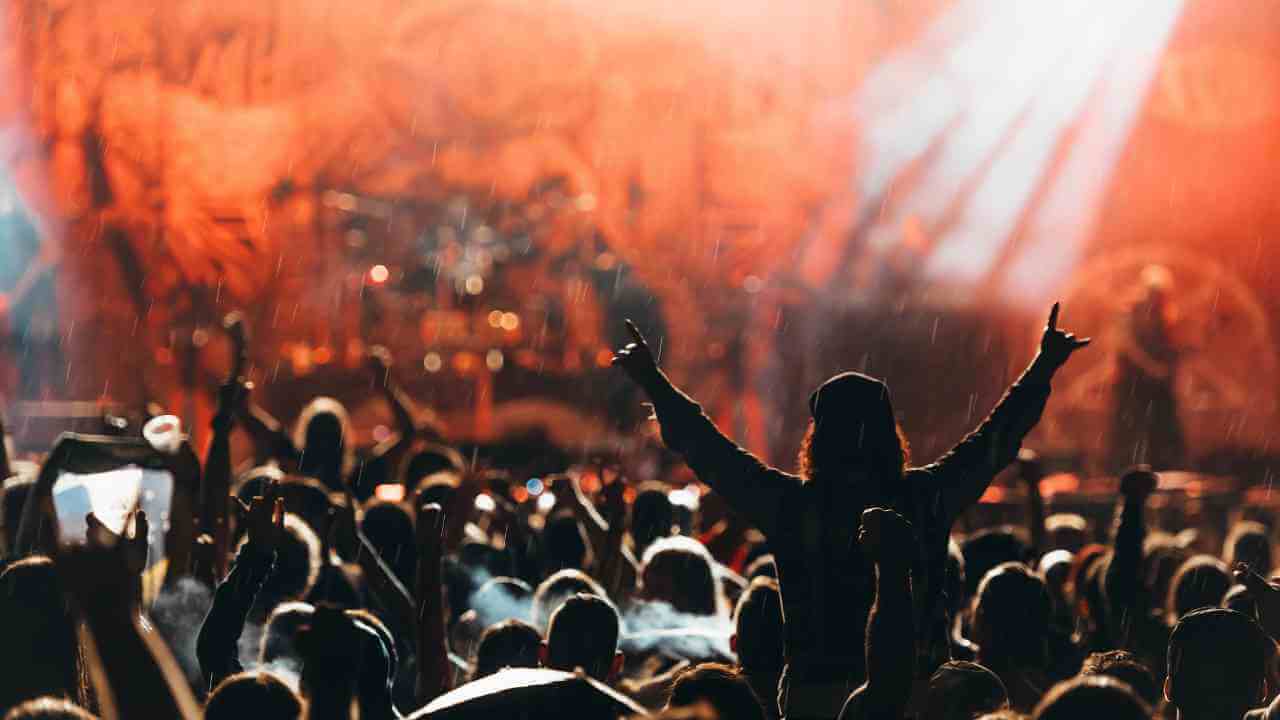 a crowd of people at a concert with their hands up in the air