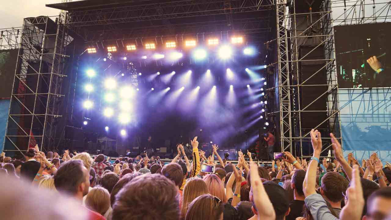 a crowd of people at a concert with their hands in the air