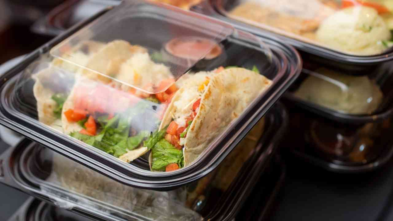 several plastic containers filled with food sitting on a table