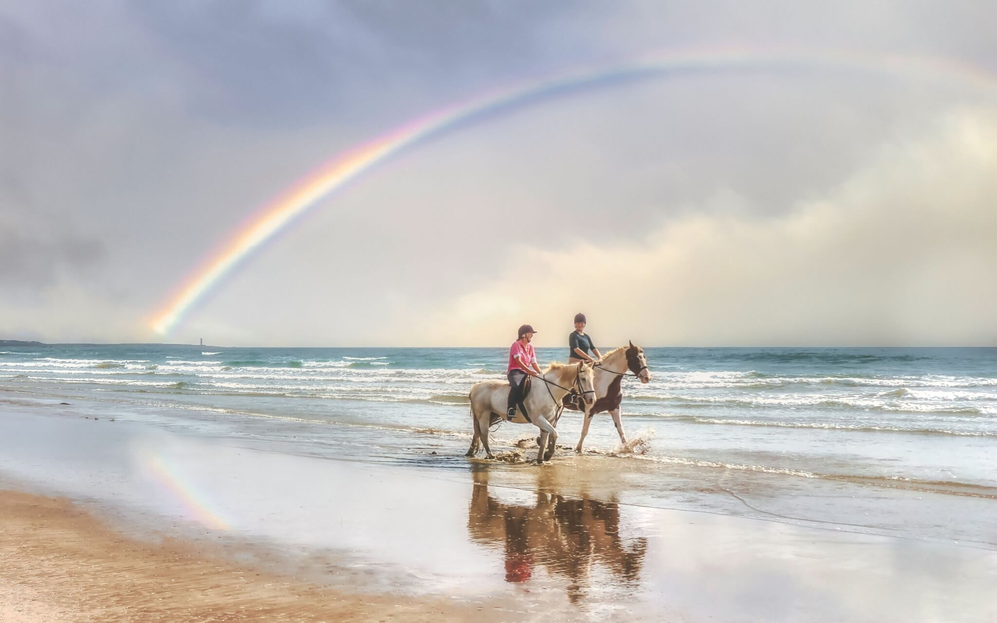 women riding horseback on the beach