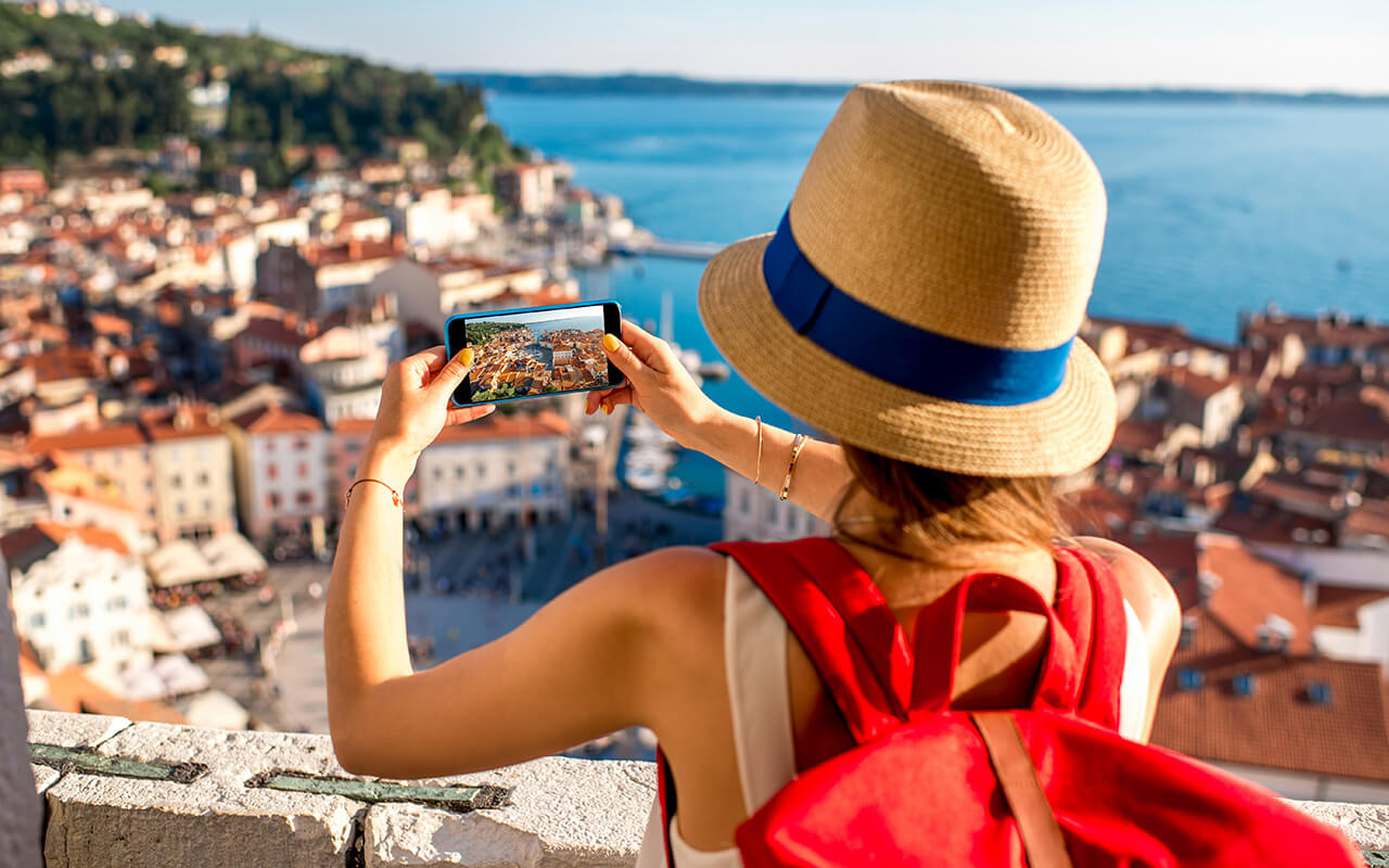 woman taking a photo on her phone at a coastal town