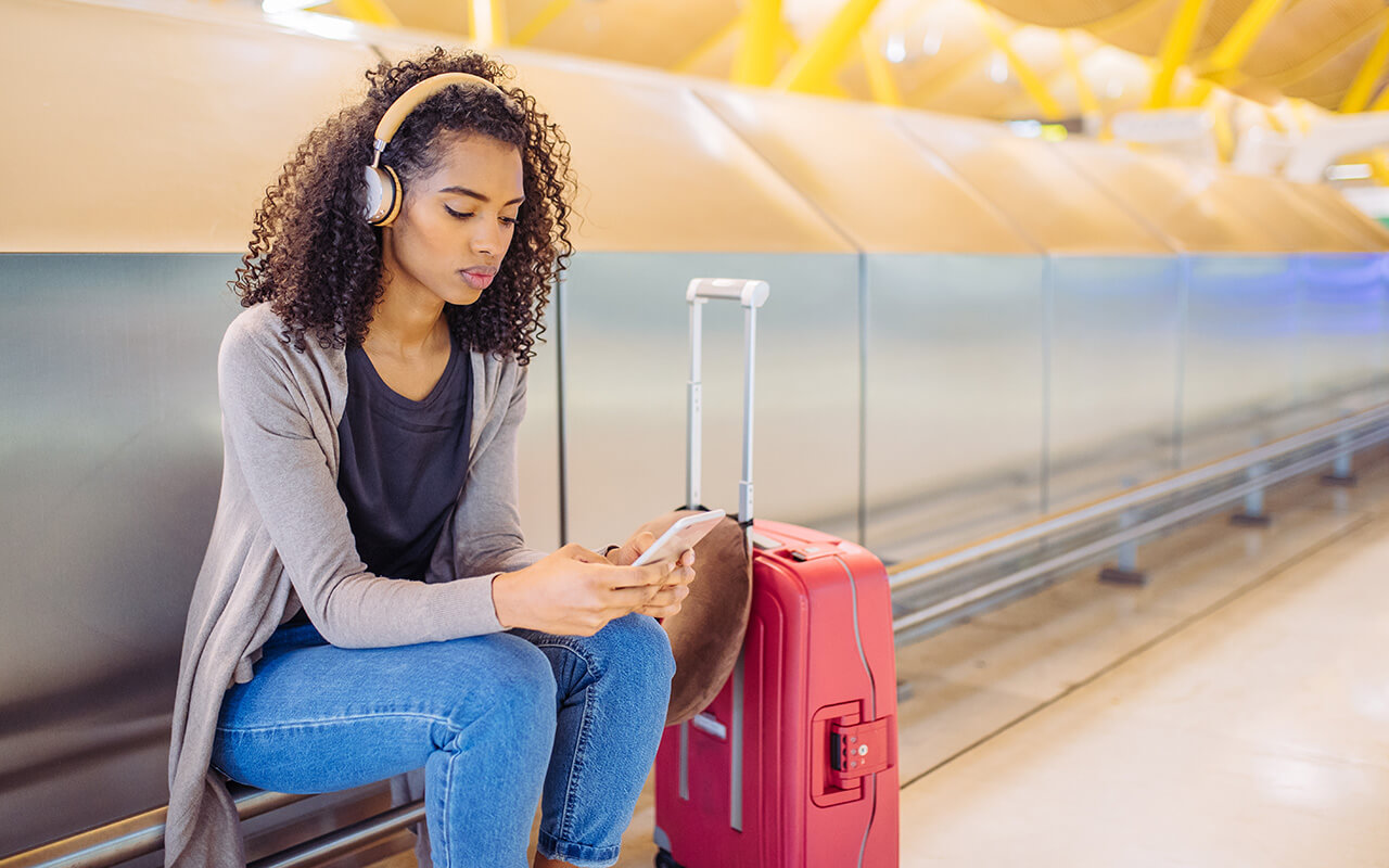 woman listening to music on headphones at an airport