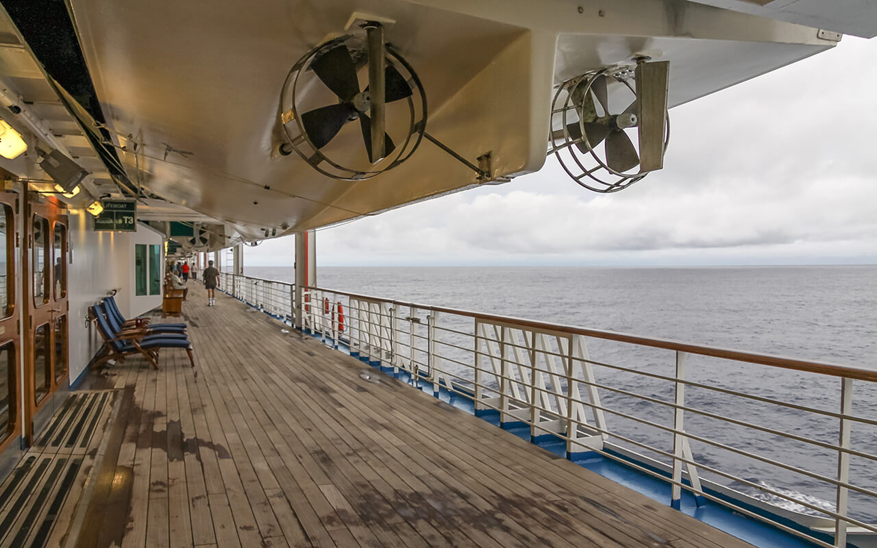 Teak lined Promenade Deck of modern cruise ship on a grey stormy day.