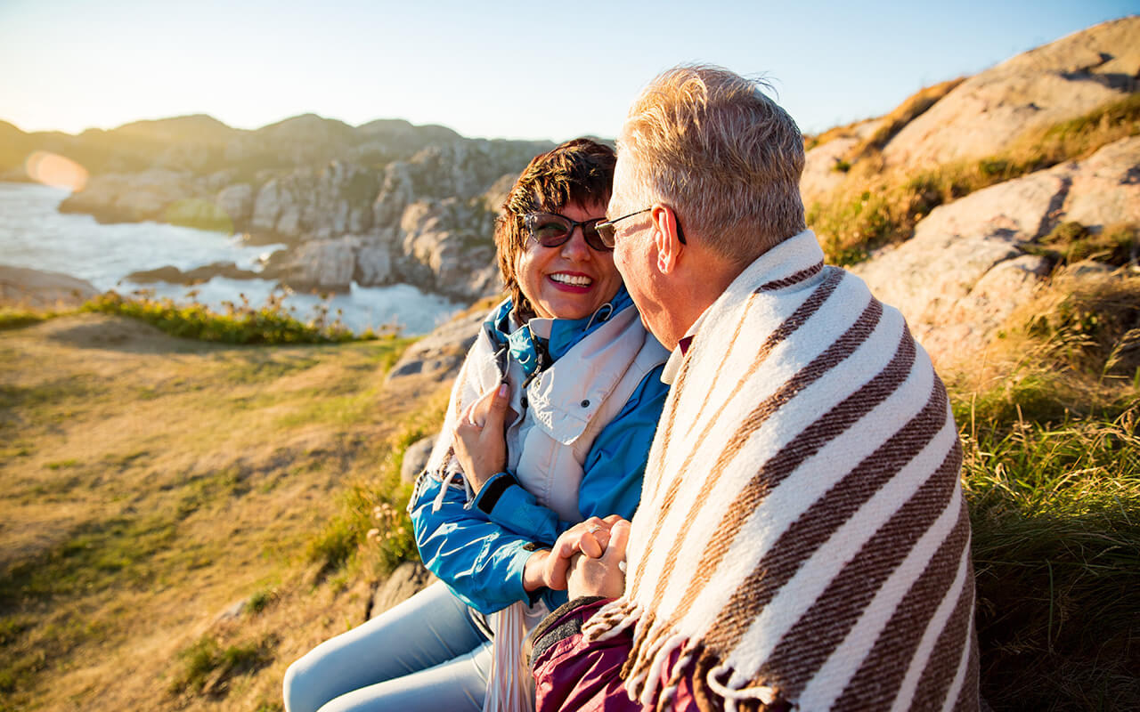 Loving couple hiking, sitting on windy top of rock, exploring.