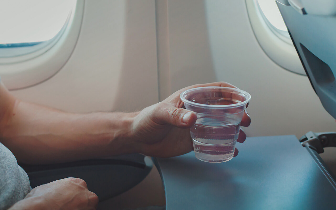 Person holding cup of water on an airplane