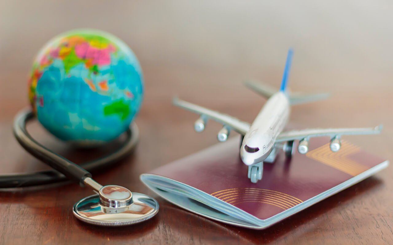 A miniature airplane on a passport with a globe and stethoscope 