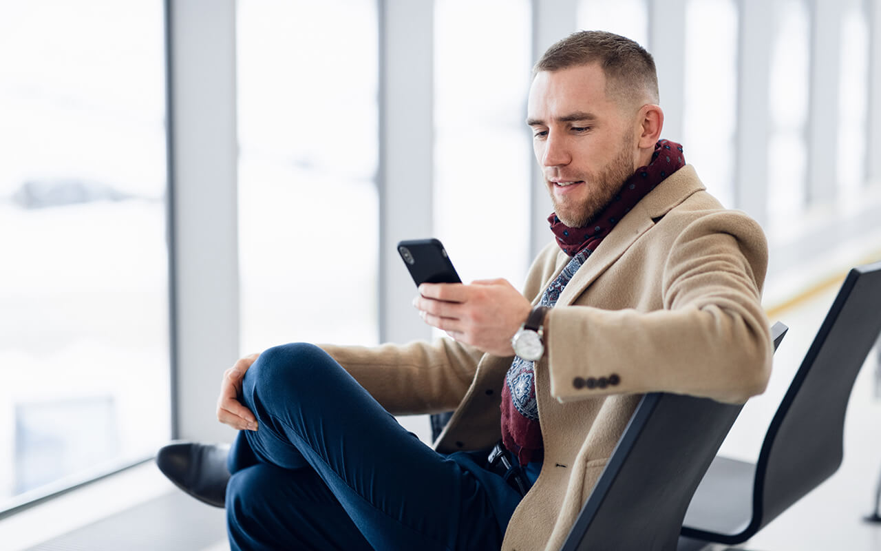 man looking at his phone at an airport