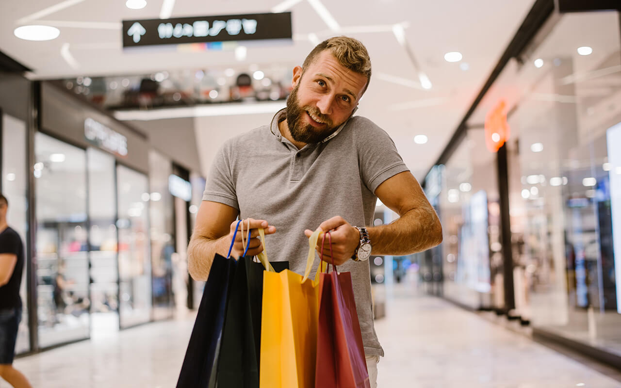 Man holding shopping bags at an airport 