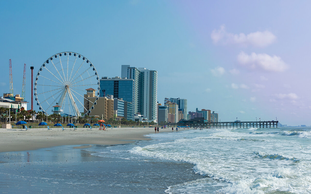 Panoramic view of Myrtle Beach, South Carolina with beach, hotels, ferris wheel, and boardwalk.