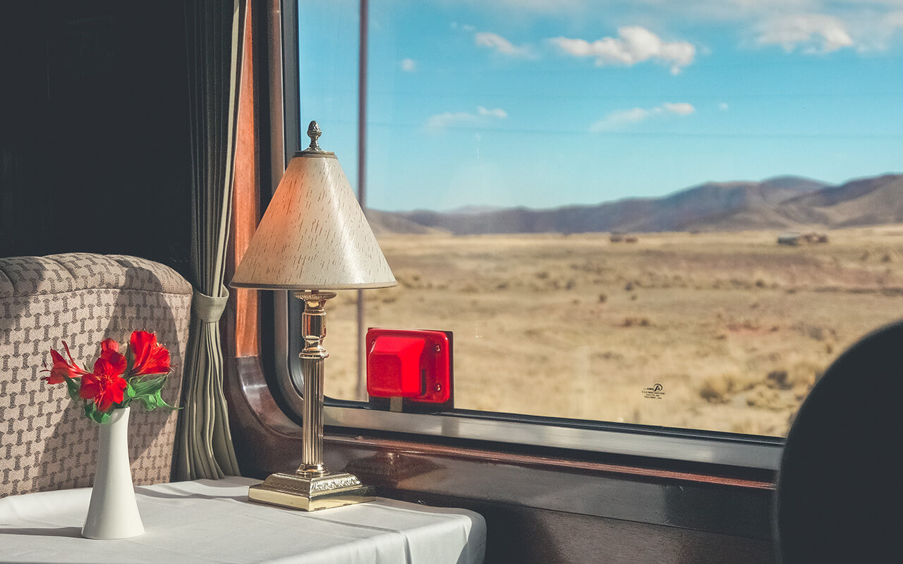 The luxury wooden decoration with comfortable sofas and fancy table lamps of the Perurail Titicaca train.