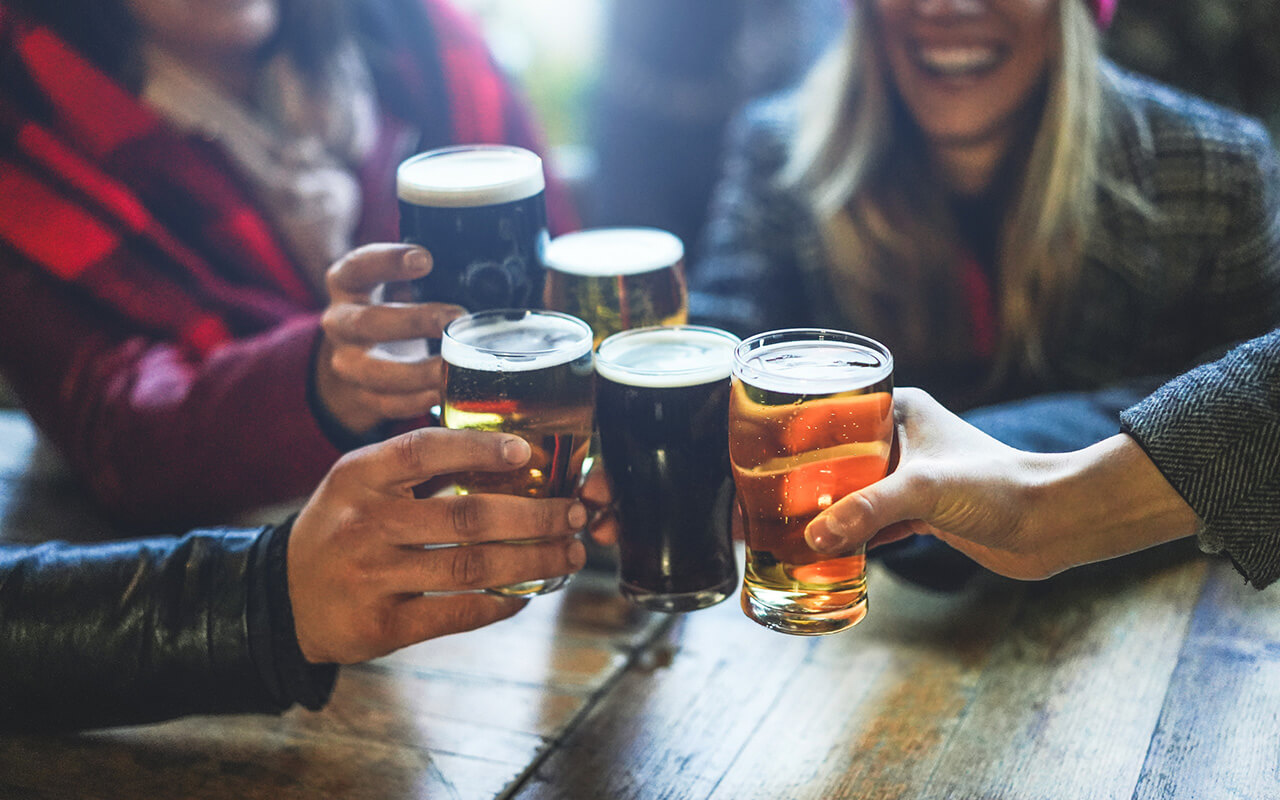 Group of happy friends drinking and toasting beer at brewery