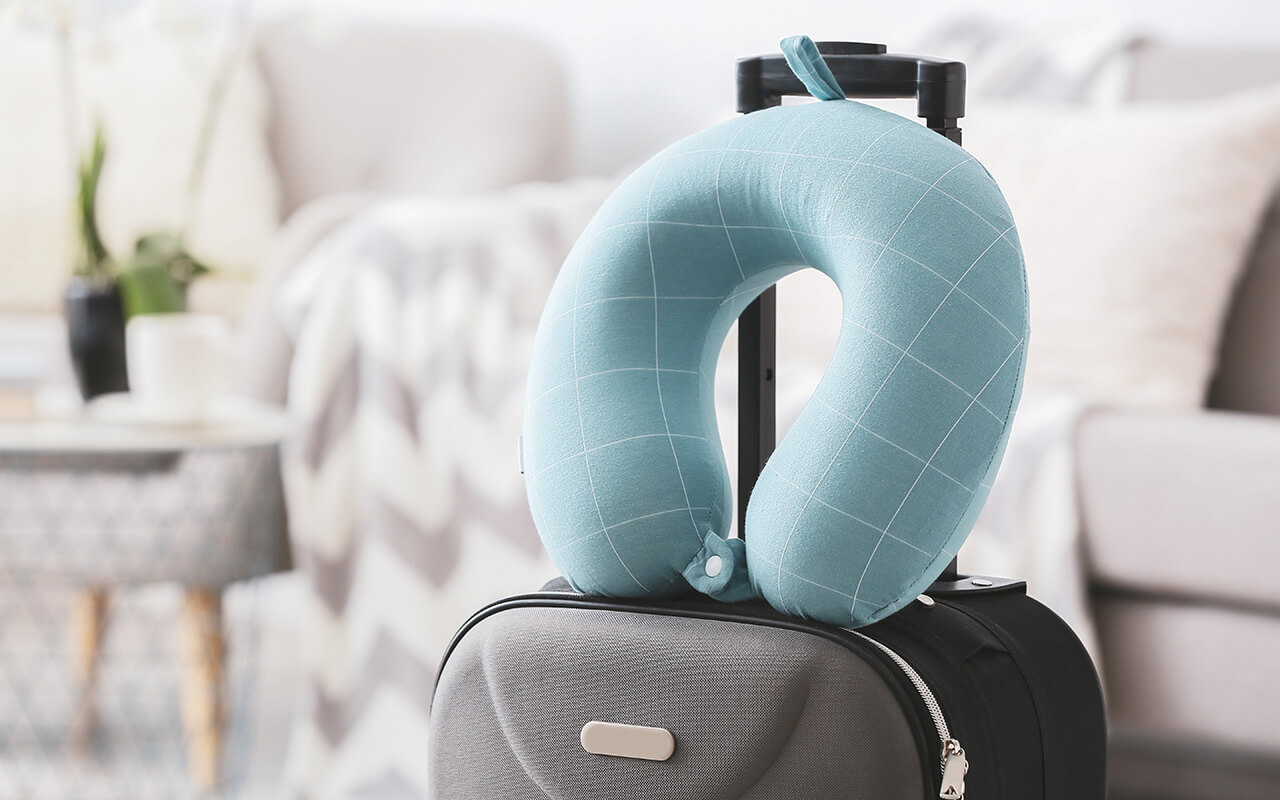 Travel pillow and suitcase in room