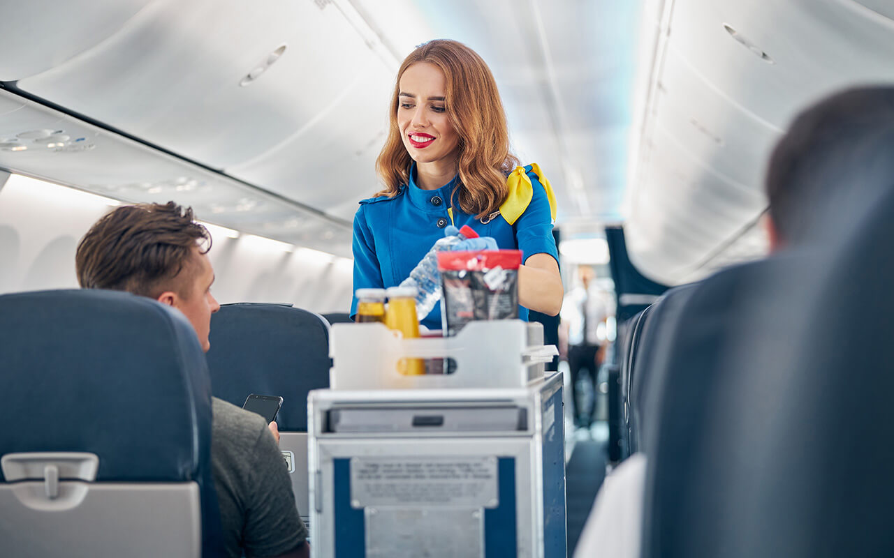 Flight attendant serving food and drinks to passengers on board