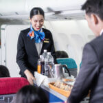 Flight attendant serving food and drink to passenger on airplane