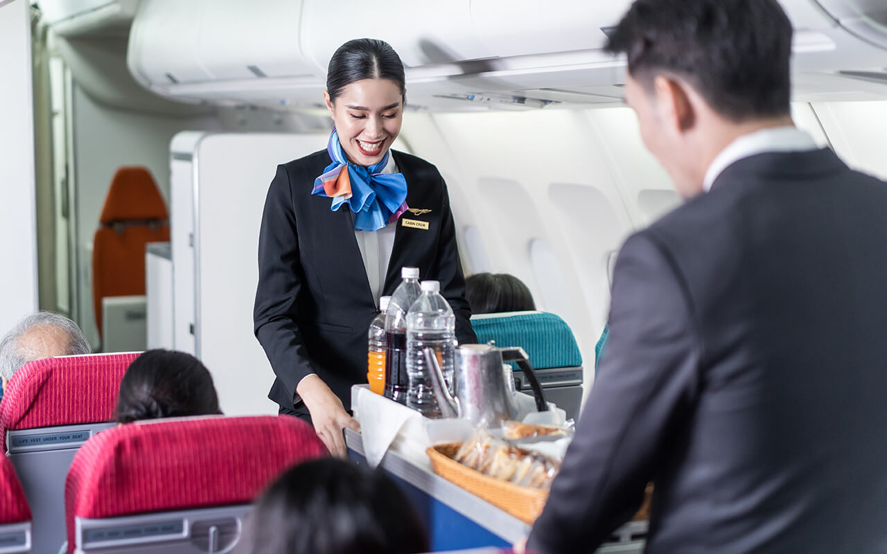 Flight attendant serving food and drink to passenger on airplane