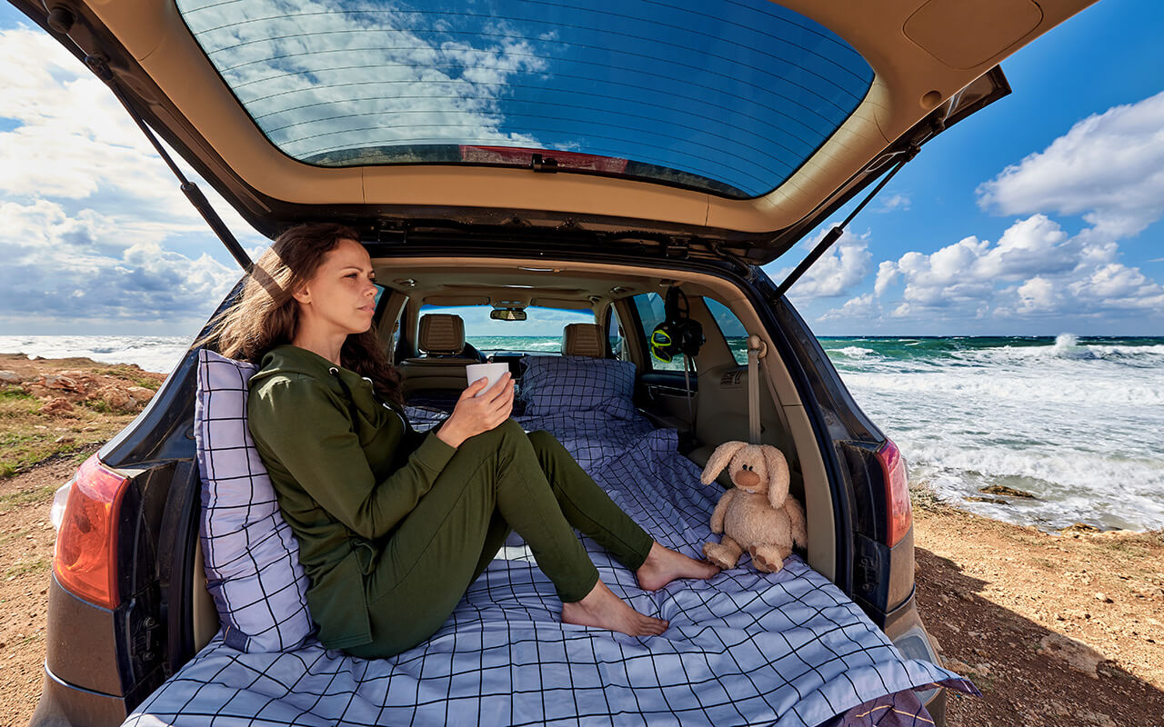 woman sleeping in her car with blankets and pillows