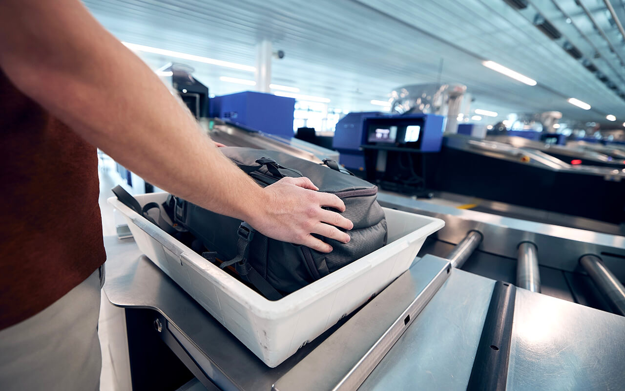 Man putting his luggage in a tray at airport security 