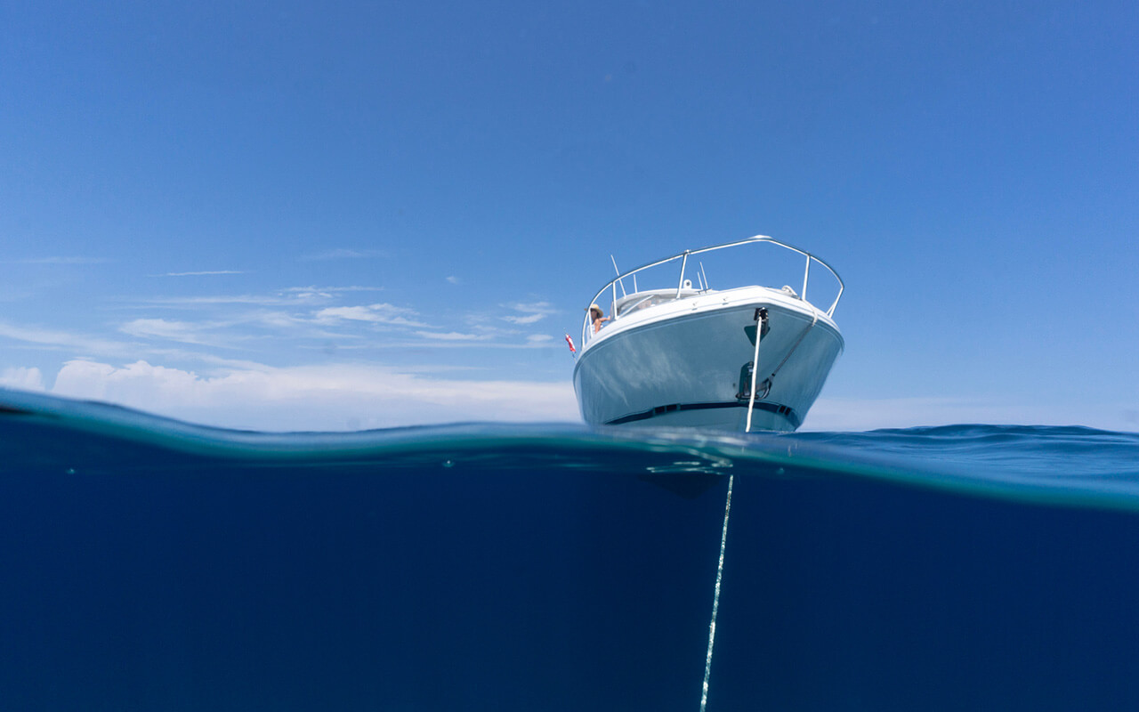 luxury boat sitting on anchor floating in deep blue water with blue sunny skies in background. 