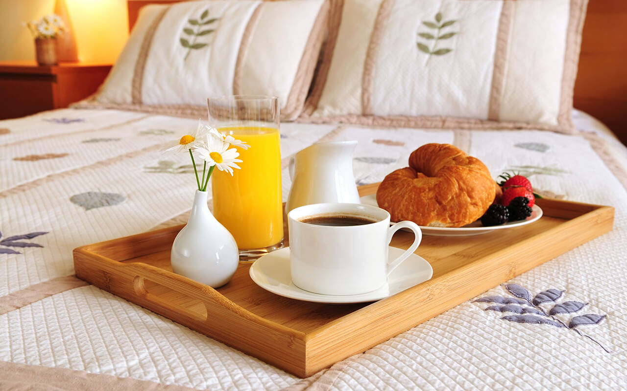 Breakfast on a bed in a hotel room