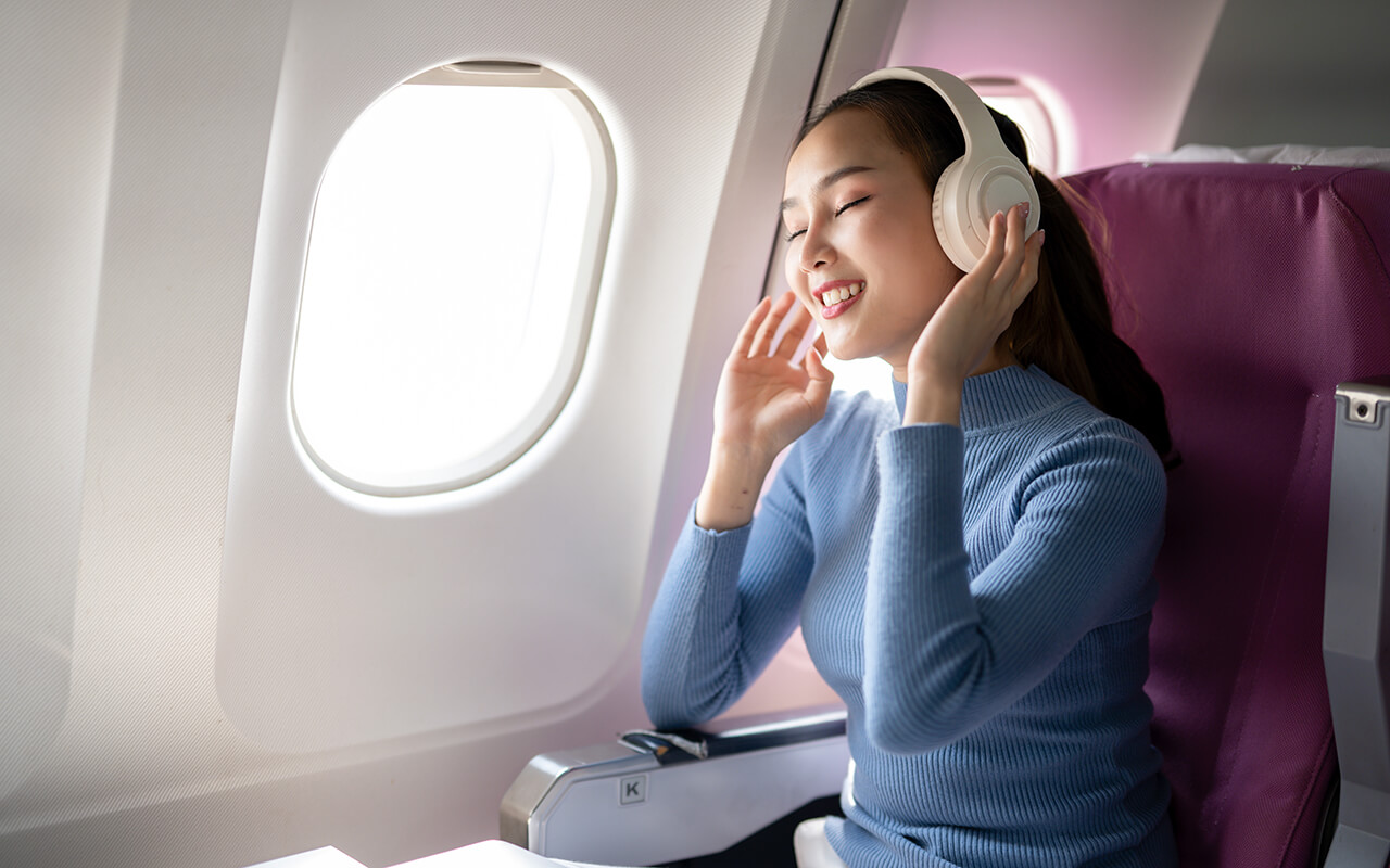 Smiling Woman with Headphones on Airplane