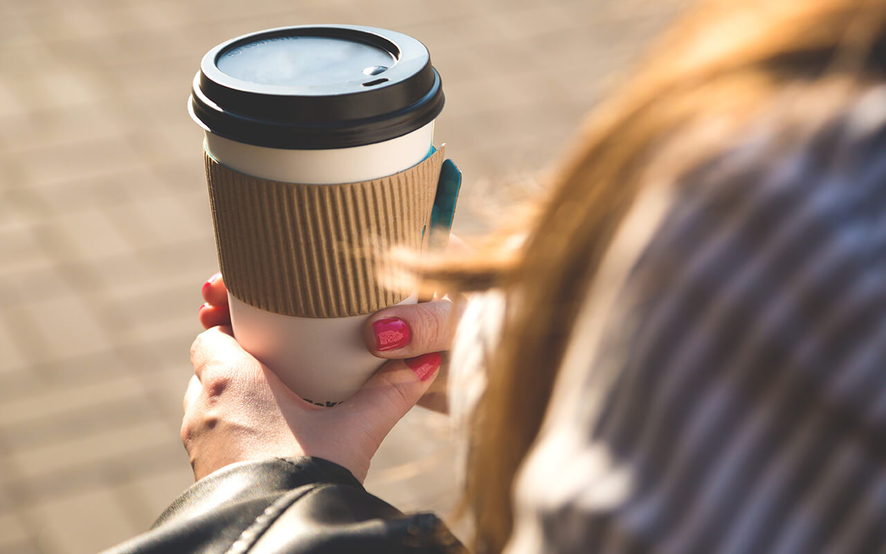 woman holding to go cup of coffee 