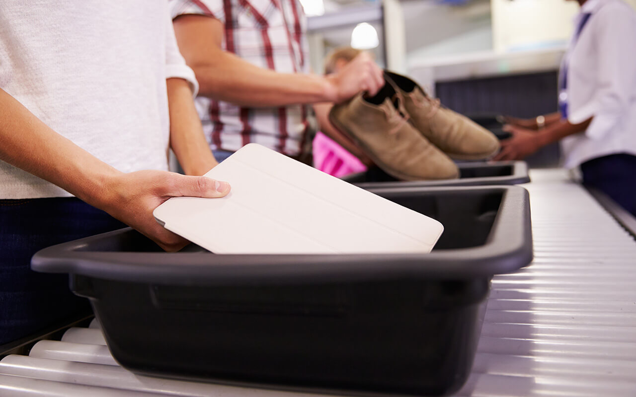 Traveler putting their laptop into security bin at the airport