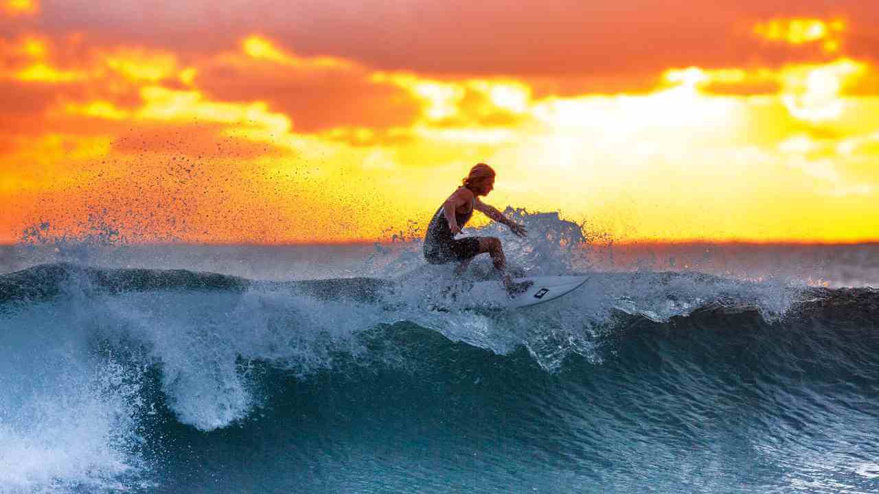 a surfer riding a wave at sunset