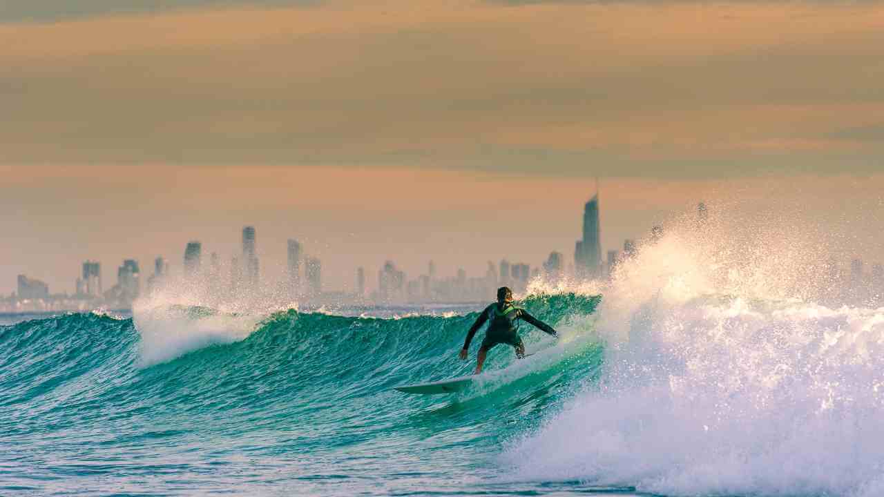 a surfer riding a wave in front of a city skyline