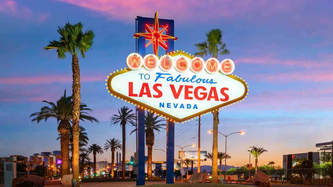 the las vegas sign at sunset with palm trees in the background