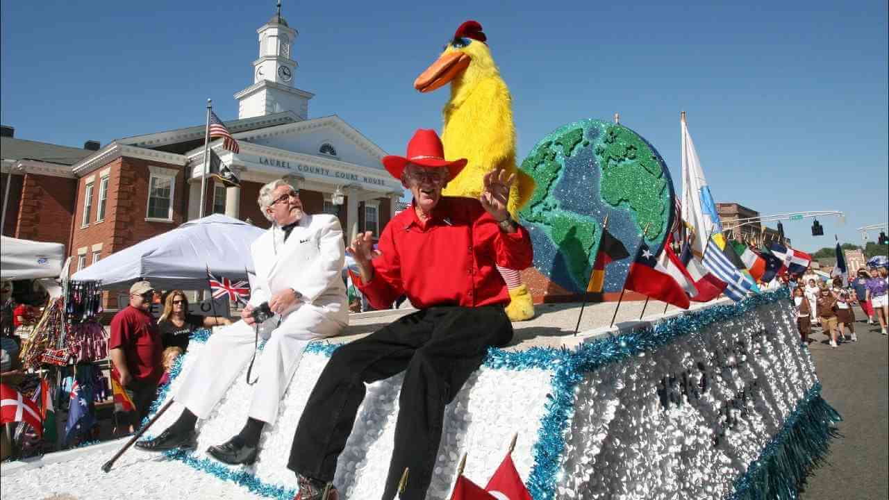 Two individuals in costumes riding on a float in a parade.