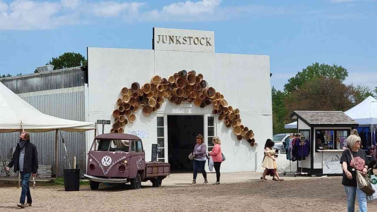 people are walking around outside of a building with an old car parked in front of it