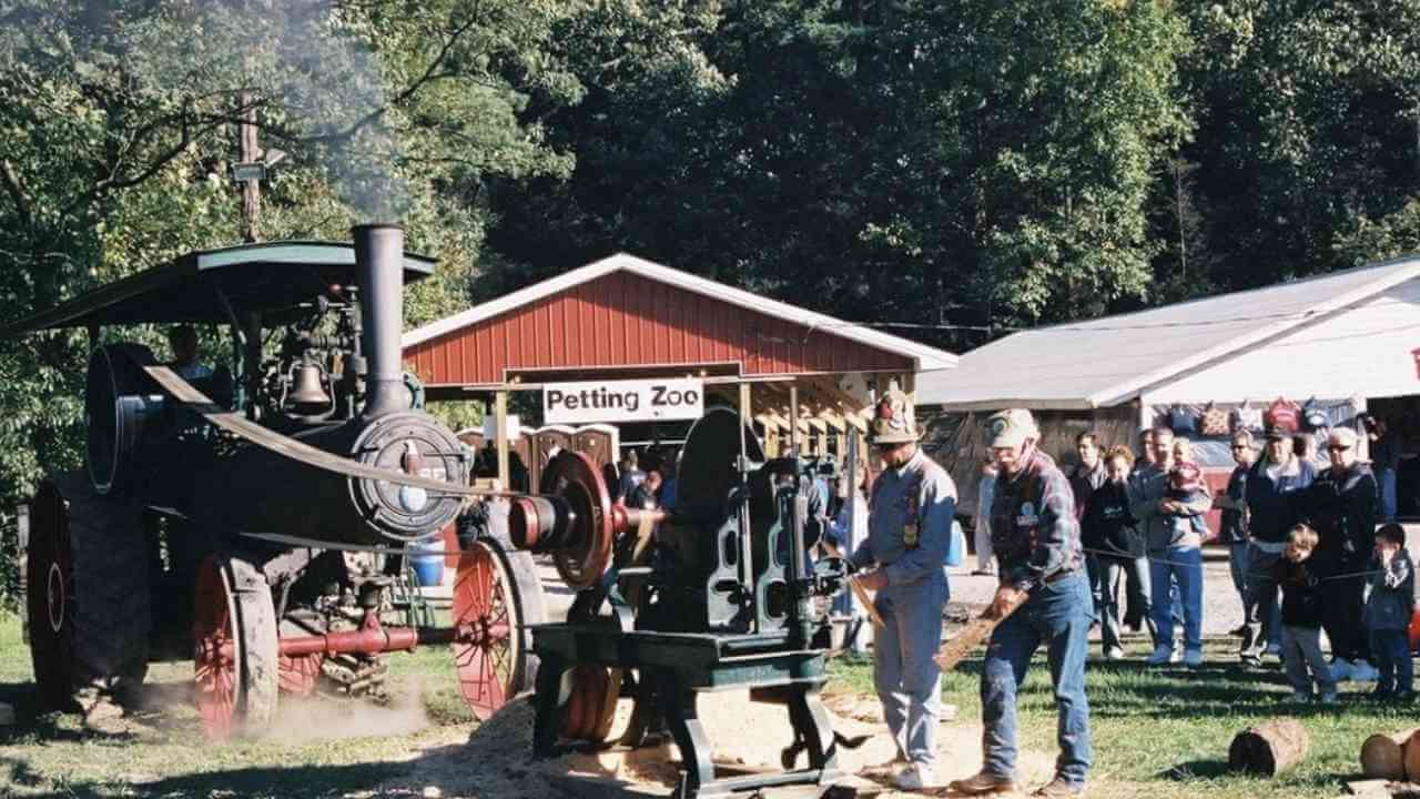 a group of people standing around an old fashioned steam engine