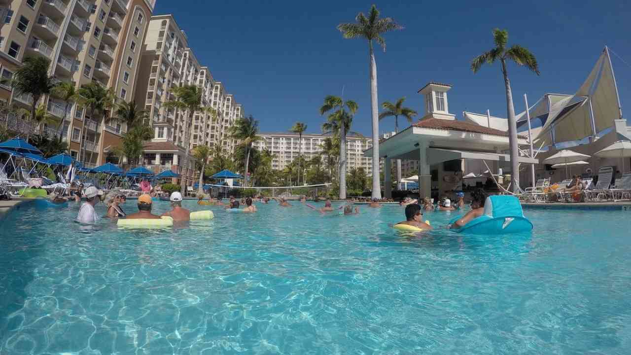 many people are swimming in the pool at a resort